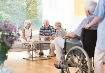 Gruppe von älteren Personen sitzt gemeinsam in einem Raum und unterhalten sich.